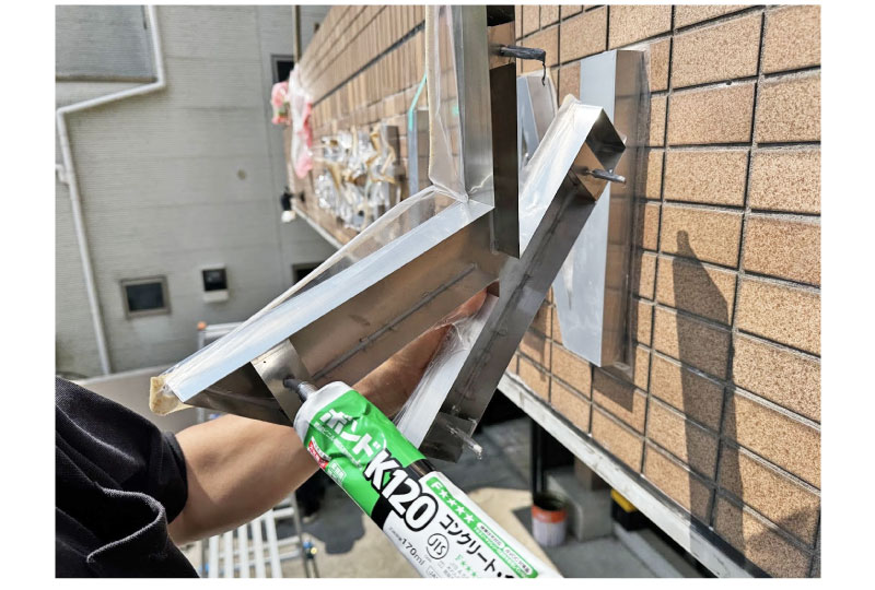 ステンレスチャンネル文字のボルトにボンドをつけて取り付ける風景